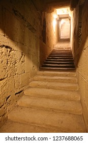 Close up indoor view of an old stone staircase leading to a lighted entrance. Abstract view of a corridor in an ancient church. Mysterious way.
