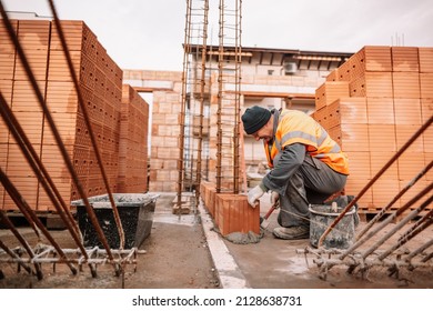 Close up of industrial bricklayer installing bricks on construction site. Construction mason building brick walls