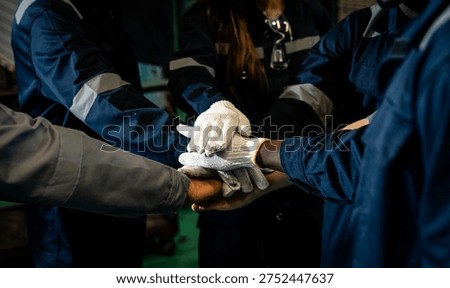 Close up of industrial workers stacking hands together to represent teamwork and collaboration inside a factory. Concept of unity, cooperation, and strong workforce support in manufacturing.