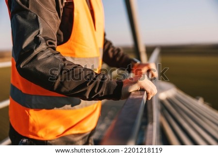 Close up of industry worker holding railing on the high metal construction.