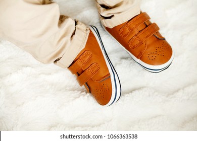 Close Up Of Infant Boy In Fashion Brown Leather Kids Shoes And Denim Pants. Stylish First Cute Little Baby Shoes