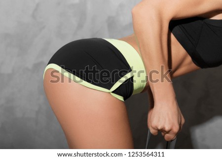 Close - up of the inflated ass fitness model in black shorts doing exercises with a sports elastic band