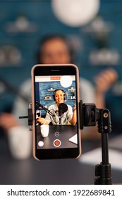 Close up of influencer vlogger record live broadcast looking at smartphone on tripod at home studio podcast. Creative content creator making online video for subscribers audience - Shutterstock ID 1922689841