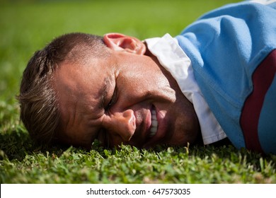 Close up of injured rugby player lying on playing field - Powered by Shutterstock