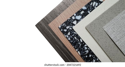 close up interior construction material samples containing grey fabric wallpaper, grainy artificial stone, black terrazzo stone, oak and walnut wooden laminateds isolated on white background.