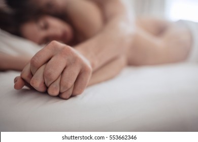 Nahaufnahme eines intimen Paares, das Händchen hält, während er Sex im Bett hat. Konzentriere dich auf die Hände.