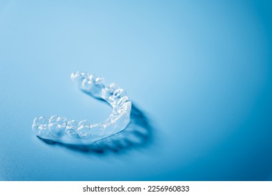 Close up invisible aligners on the blue background with copy space. Plastic braces dentistry retainers to straighten teeth - Shutterstock ID 2256960833