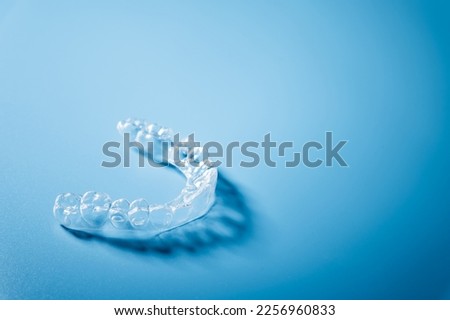 Close up invisible aligners on the blue background with copy space. Plastic braces dentistry retainers to straighten teeth