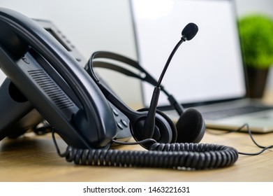 Close Up IP Telephone With Head Set On Wood Table And Blurred Of Laptop Computer On Background