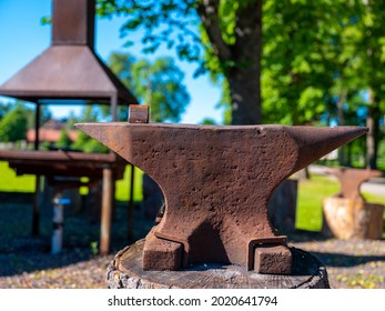 Close up of an iron anvil outdoors. Heating stove and second anvil blurred but visible in background. Shot in Sweden, Scandinavia