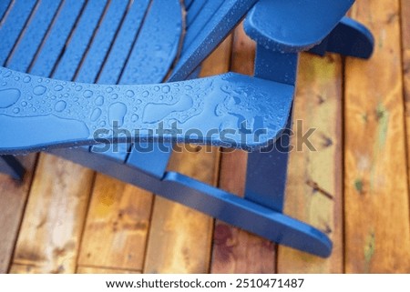 Close up isolated image of arm of composite deck chair. Wood wooden floating dock. After the rain rainfall raindrops wet beading water. Cottage country northern Ontario Canada. Muskoka Adirondack.