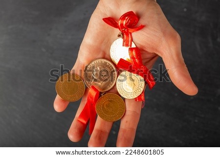 Close up isolated image of assorted sizes of Turkish gold coins including cumhuriyet, yarim and ceyrek in a white woman's hand . Some are attached to red ribbons for giving as gifts in weddings.