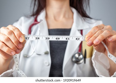 Close up isolated image of a caucasian doctor holding a tape measure in her hands which shows 40 inches as abdominal circumference upper limit in healthy people. Concept for weigh loss and fitness.