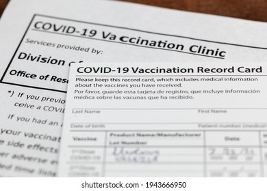 Close Up Isolated Image Of A COVID 19 Vaccination Record Card On A Wooden Desk. The Card Details The Date, Type And The Dose Number Of Administred Vaccine And Given To Every Person For Record.
