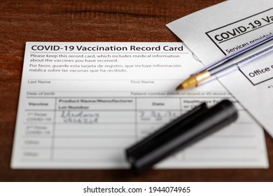 Close Up Isolated Image Of A COVID 19 Vaccination Record Card On A Wooden Desk. The Card Details The Date, Type And The Dose Number Of Administered Vaccine And Given To Every Person For Record.