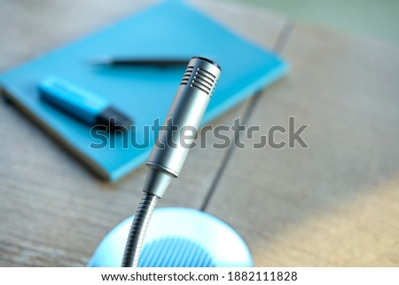 Close up of an isolated microphone, intercom on a table, from above, with notebook and pen in the blurred background, selective focus