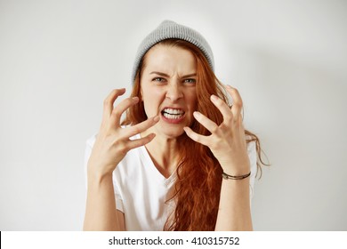 Close up isolated portrait of young annoyed angry woman holding hands in furious gesture. Young female with red hair in white T-shirt and cap. Negative human emotions, face expressions. Film effect  - Shutterstock ID 410315752