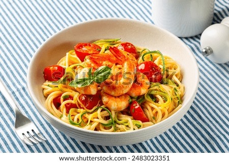 Close up of italian pasta. Prawn, tomato and courgette, or zucchini, spaghetti plate on textile runner.