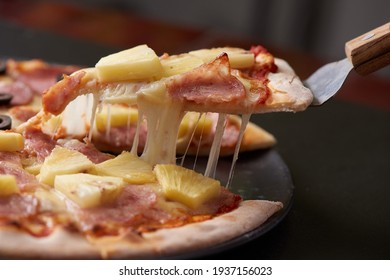 Close up Italian pizza about cheese it stick, Selective focus, mozzarella and tomato sauce. Pizza on a black stone background, Pizza slice melted cheese food.