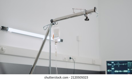 Close Up Of IV Drip Bag And Empty Hospital Ward Bed. Nobody In Emergency Room For Reanimation And Intesive Care With Heart Rate Monitor And Oxygen Tube. Space For Healthcare Recovery