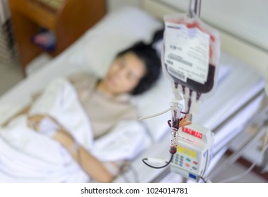 Close up IV set, add blood and blurry of patient illness sleeping on hospital bed. Donation bone marrow transplant, Medical concept.