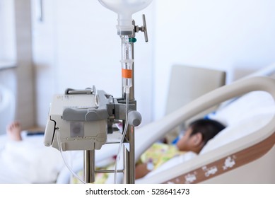 Close Up IV Set And Blurry Illness Asian Boy Sleeping On Hospital Bed.Medical Equipment Concept.