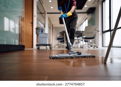 Close up of janitor using mop while cleaning office floors. Copy space. 