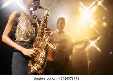 Close up of jazz music duo band performing on stage during live music concert with young woman playing saxophone in foreground, copy space - Powered by Shutterstock