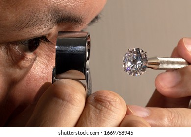 Close up jeweller asian man looking through loupe polished diamond. Diamond view. Diamonds grading.