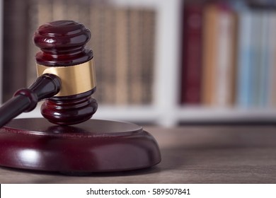 Close up of a judge gavel and law books in the background of a courtroom. Selective focus