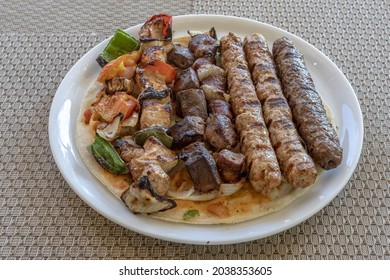 A Close Of Kebab, Meat, And Of Shish Taouk On A White Plate On A Gray Decorated Surface