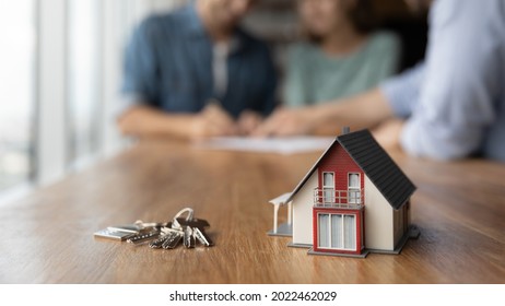 Close up of key and tiny toy house on table. Married couple buying house, consulting, lawyer, legal advisor, real estate agent, bank manager, signing mortgage agreement in background - Shutterstock ID 2022462029