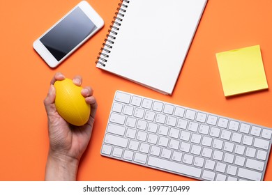 Close Up Of  Keyboard Computer, Stress Ball In Hand  With Orange Table Background, Stress Concept