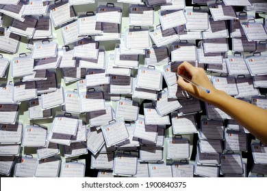 Close Up Of Kid Hand Writing His Wish List Message On Sticky Post-it Paper Along With Other Hundreds Of People's Wishes Attached To Light Green Wall. Wishlist, Plan And New Year Resolution Background.