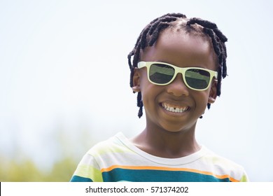 Close Up Of A Kid With Sunglasses Smiling On A Park