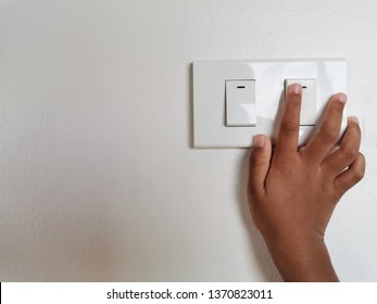 Close Up Forefinger’s Kid Is Turning On Or Turning Off The Light-switch With Grey Wall.