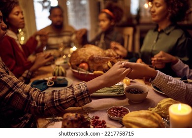 Close of kids saying grace while having Thanksgiving dinner with their family at dining table.  - Shutterstock ID 2217758715