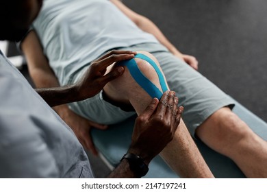 Close up of kinesio taping at knee of senior man in rehabilitation clinic, copy space - Powered by Shutterstock