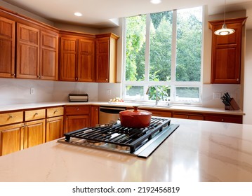 Close Up Of Kitchen Stovetop With Stone Counter Top, Cherry Cabinets And A Large Window With Daylight Coming In 