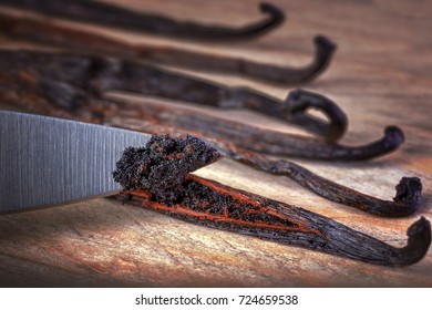 Close Up Of Knife Cutting Vanilla Beans Seed Pods On Wooden Background