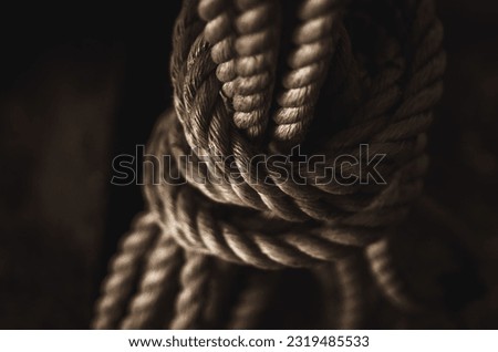 Close up knot of the marine rope. Object is in dark and moody colors. Selective focus, shallow depth of field, blurred background.
