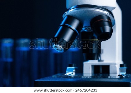 Close up of laboratory microscope with set of test tubes with blue liquid