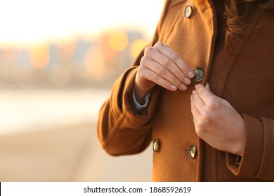 Close Up Of A Lady Fastening Button Of Coat On The Beach In Winter At Sunset