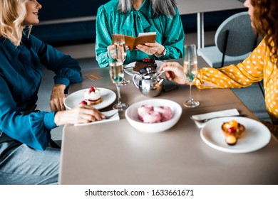 Close Up Of Lady Holding Restaurant Bill While Sitting At The Table With Female Friends Stock Photo