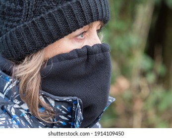 A Close Up Of A Lady Wearing A Black Wool Hat And Snood Covering Her Face With Just Her Eyes Showing.She Looks Ahead And Has Long Hair Hanging From Under The Hat.