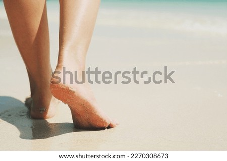 Close up of a lady woman's bare feet walking and footprint at wet on the beach. Vacation on ocean beach, foot on sea sand. Leave empty copy space Enter the text. Shadow from the sun hits the sand.