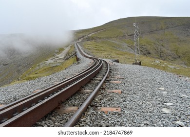 Close Up Landscaped Image Of Railway Train Tracks Going Into Distance On Top Of Snowdonia, Wales Mountain Range On A Cloudy Spring Day