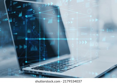 Close up of laptop computer with abstract cube hologram on blurry background. Metaverse, software, future and data center concept. Double exposure
