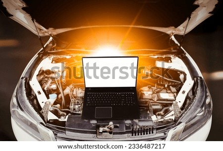 Close up of laptop computer with blank screen on car engine compartment background. Car maintenance service concept.