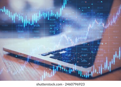 Close up of laptop computer with creative candlestick forex chart with index on blurry background. Trade, finance and stock exchange concept. Double exposure